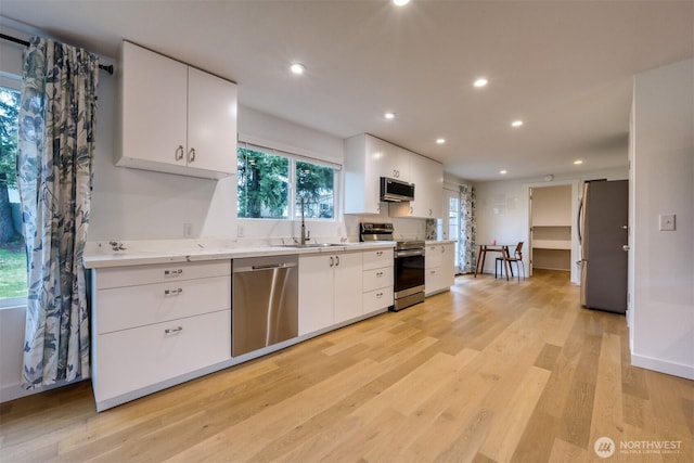 kitchen featuring recessed lighting, light wood-style flooring, appliances with stainless steel finishes, white cabinetry, and a sink