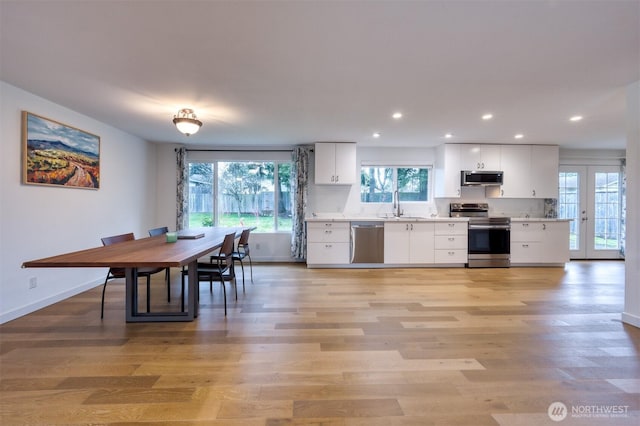 kitchen featuring light wood finished floors, light countertops, appliances with stainless steel finishes, white cabinets, and a sink