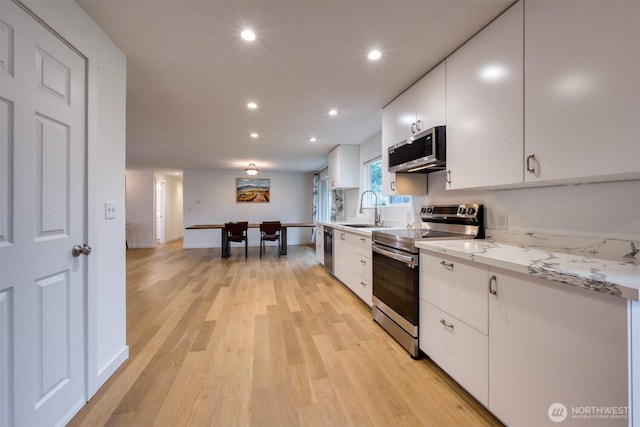 kitchen featuring recessed lighting, stainless steel appliances, a sink, white cabinetry, and light wood-type flooring