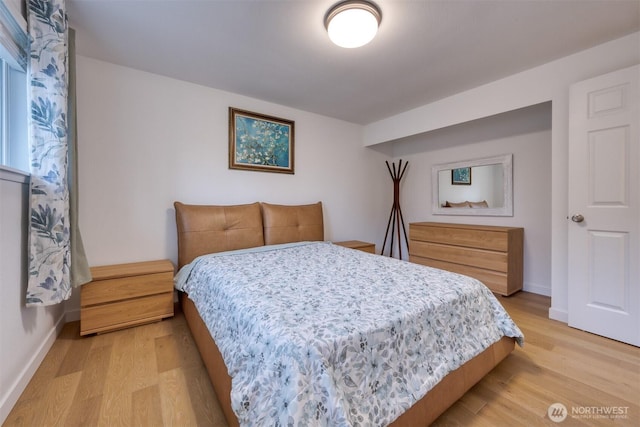 bedroom featuring light wood finished floors and baseboards