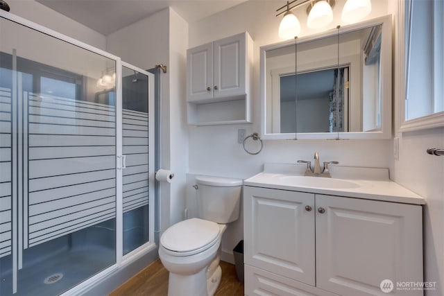 full bathroom featuring toilet, a shower stall, wood finished floors, and vanity