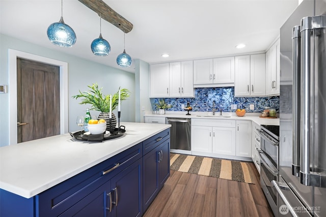 kitchen featuring decorative backsplash, stainless steel appliances, light countertops, blue cabinetry, and a sink