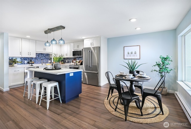 kitchen with stainless steel appliances, white cabinets, a kitchen island, and baseboard heating