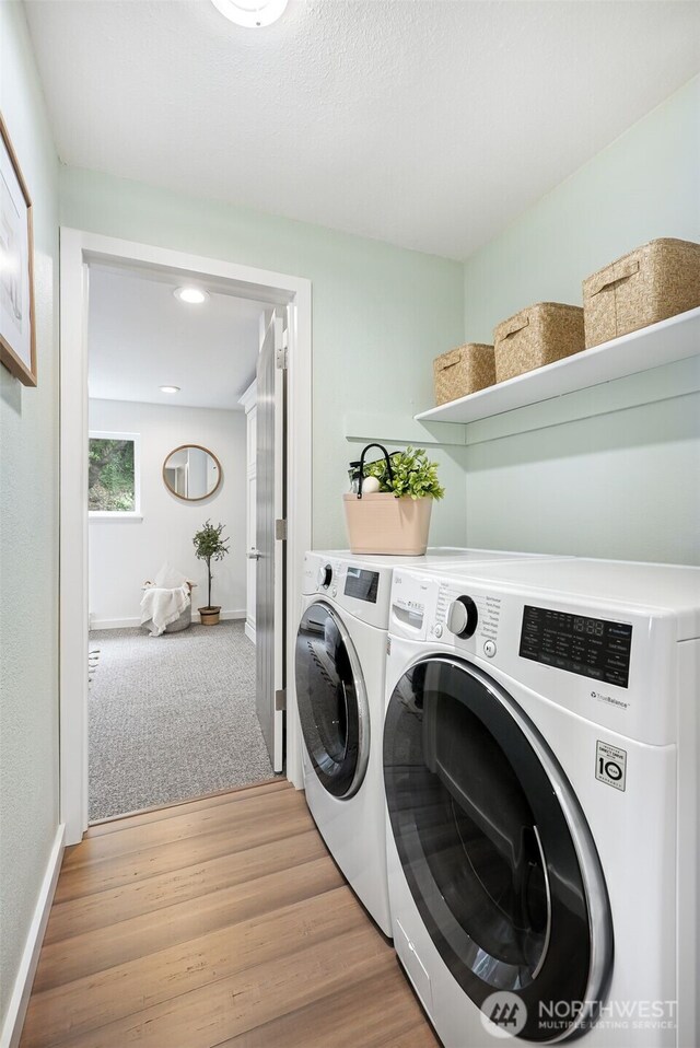 washroom featuring laundry area, light wood finished floors, washing machine and dryer, and baseboards