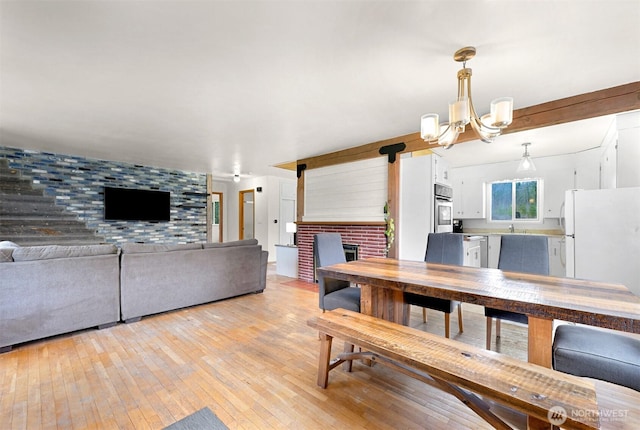 dining room featuring an accent wall, a fireplace, light wood-style flooring, and an inviting chandelier