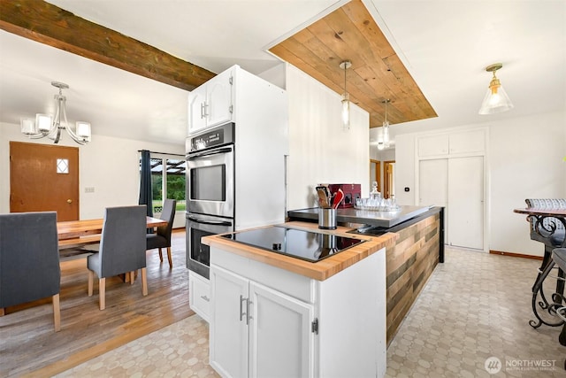 kitchen featuring double oven, white cabinetry, and decorative light fixtures