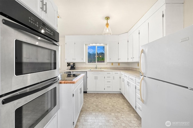 kitchen with white cabinets, light countertops, decorative light fixtures, and freestanding refrigerator