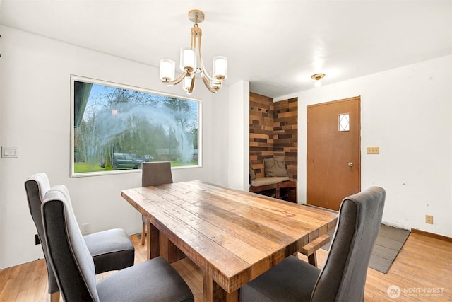 dining space featuring a healthy amount of sunlight, light wood-type flooring, and an inviting chandelier