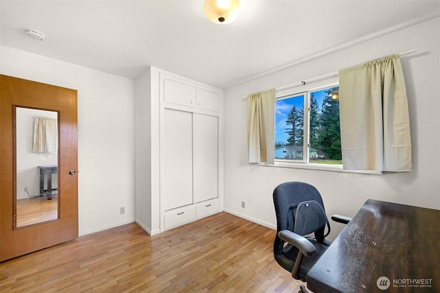 home office with light wood-style flooring and baseboards