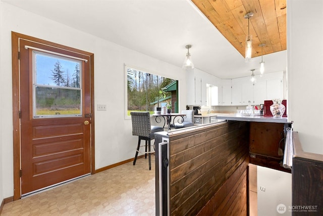 kitchen featuring decorative light fixtures, light floors, light countertops, white cabinetry, and baseboards