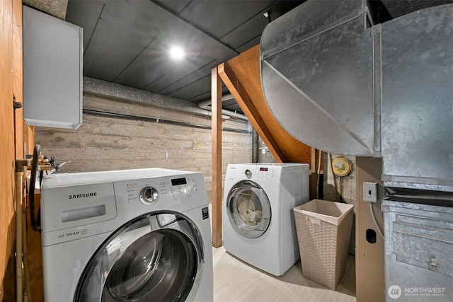 laundry area with laundry area, wooden walls, and washing machine and clothes dryer