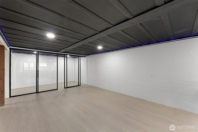 unfurnished room with concrete block wall and light wood-style flooring