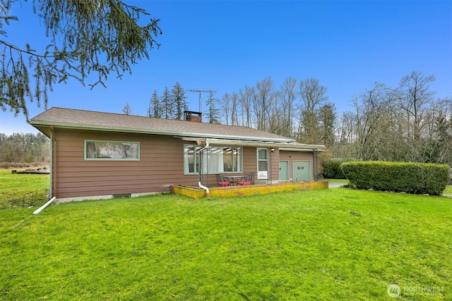 back of property with a patio area, a yard, a chimney, and an attached garage