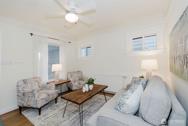 living room with baseboards, ceiling fan, radiator heating unit, and wood finished floors