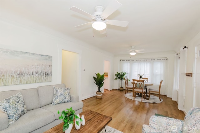 living room with ceiling fan, light wood-style flooring, and baseboards