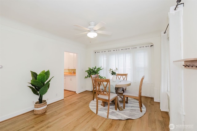 dining area with baseboards, ceiling fan, and light wood finished floors