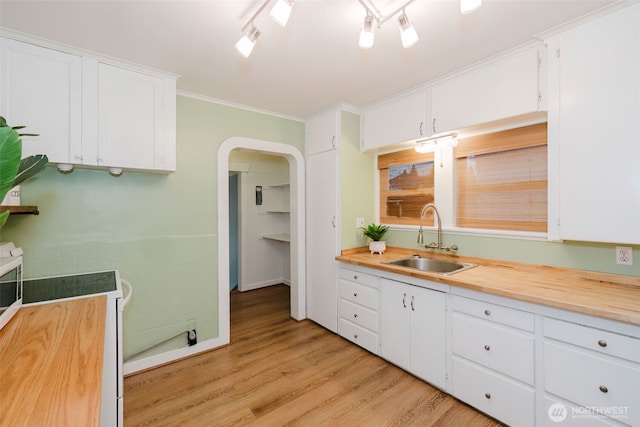 kitchen with arched walkways, white cabinets, white electric range, light wood-style floors, and a sink