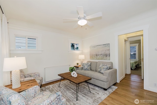 living area featuring radiator heating unit, ornamental molding, ceiling fan, and wood finished floors