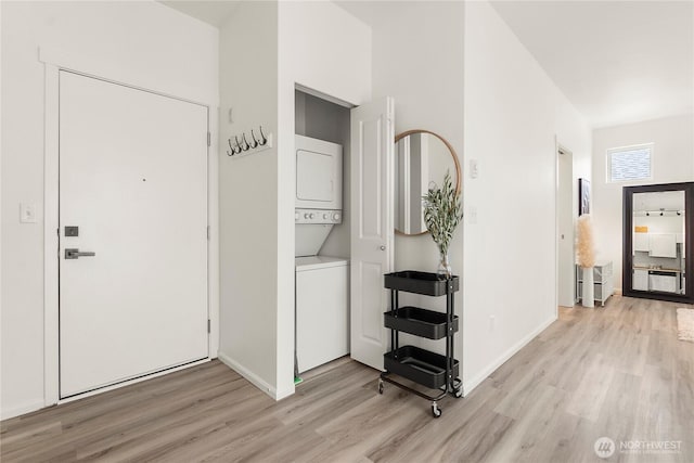 corridor with baseboards, light wood-style flooring, visible vents, and stacked washer / drying machine