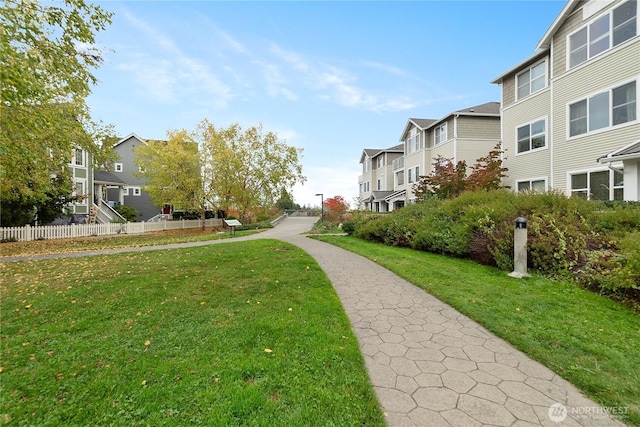 view of community featuring a residential view, a yard, and fence