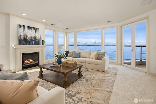 living room with a water view, a healthy amount of sunlight, crown molding, and carpet flooring