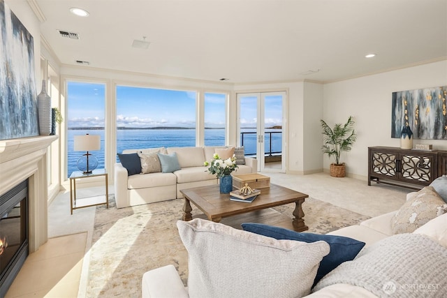 living room with light carpet, a water view, a glass covered fireplace, visible vents, and recessed lighting