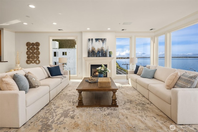 living room with recessed lighting, a glass covered fireplace, and a water view