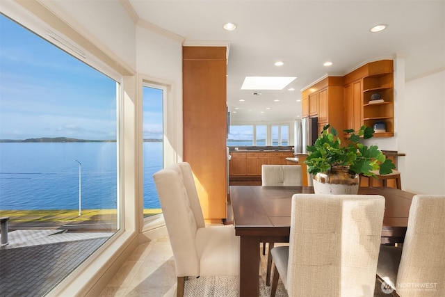 dining space with a skylight, a water view, and recessed lighting