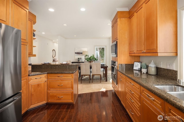 kitchen featuring dark stone countertops, brown cabinets, appliances with stainless steel finishes, dark wood-type flooring, and recessed lighting