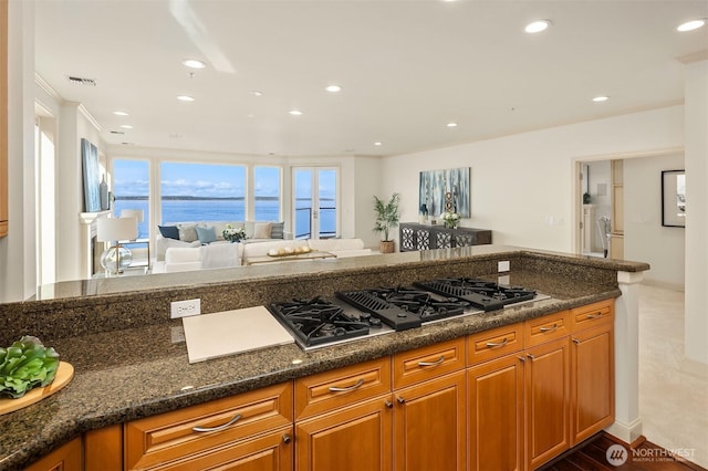 kitchen featuring brown cabinets, open floor plan, a water view, visible vents, and recessed lighting