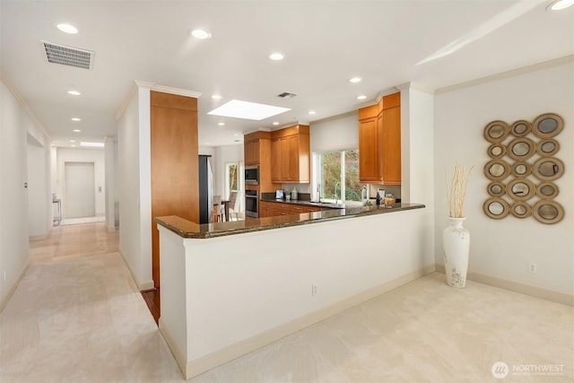 kitchen with stainless steel appliances, visible vents, recessed lighting, light colored carpet, and brown cabinetry