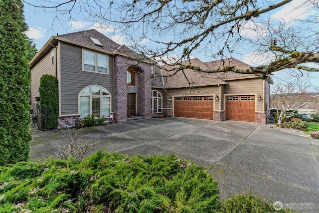 view of front facade with a garage, roof with shingles, concrete driveway, and brick siding