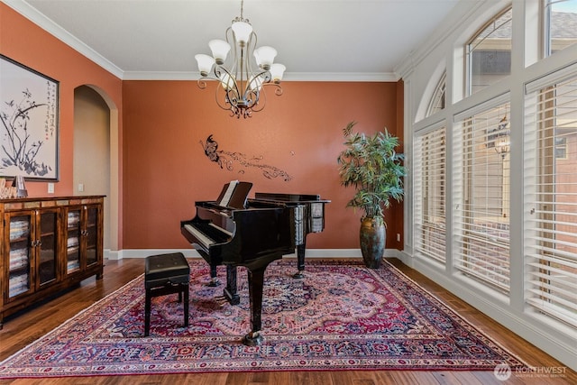 living area with arched walkways, crown molding, baseboards, and wood finished floors