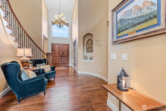 foyer with an inviting chandelier, baseboards, stairway, and dark wood-type flooring