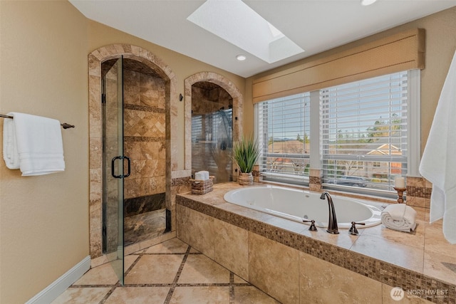 bathroom featuring a skylight, a stall shower, baseboards, a bath, and recessed lighting