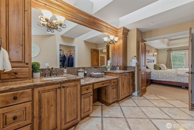 bathroom with ensuite bathroom, double vanity, a sink, and a chandelier