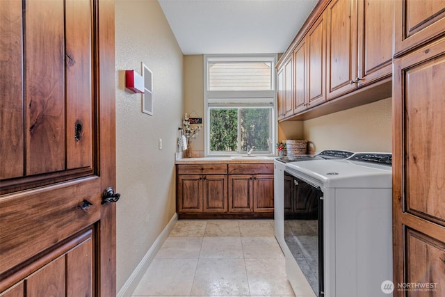 laundry room featuring light tile patterned flooring, washing machine and dryer, a sink, baseboards, and cabinet space