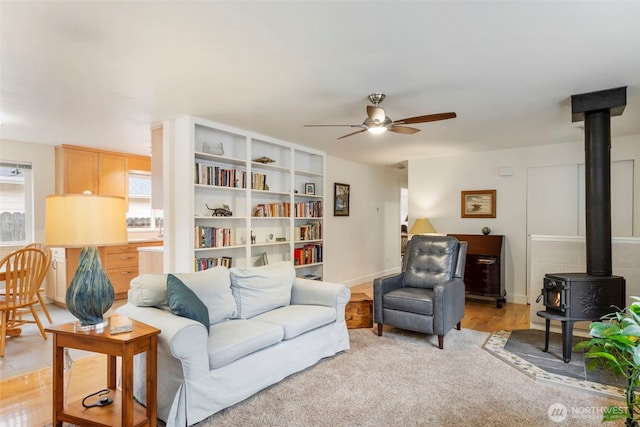 living area featuring a wood stove and ceiling fan