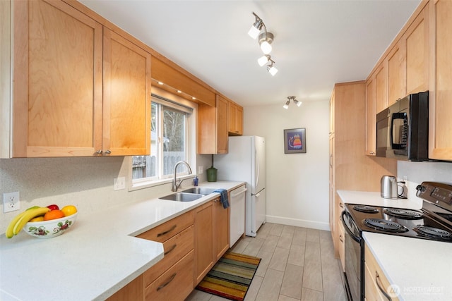 kitchen with black appliances, light brown cabinets, a sink, light countertops, and baseboards