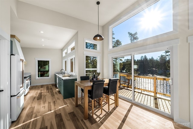 dining room with baseboards, recessed lighting, a towering ceiling, and light wood-style floors