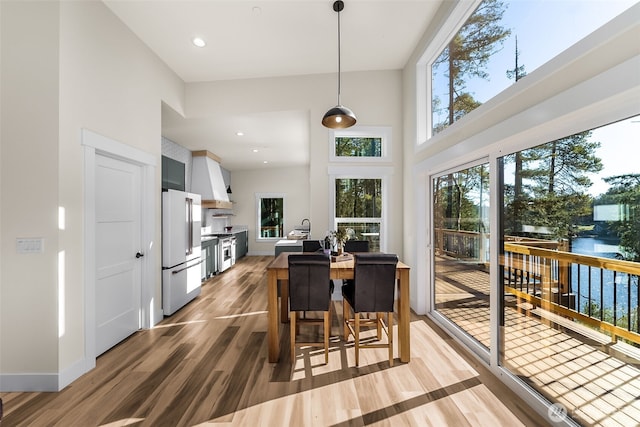 dining space with baseboards, wood finished floors, a towering ceiling, and recessed lighting