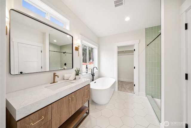 bathroom with a freestanding tub, vanity, visible vents, a shower stall, and a walk in closet