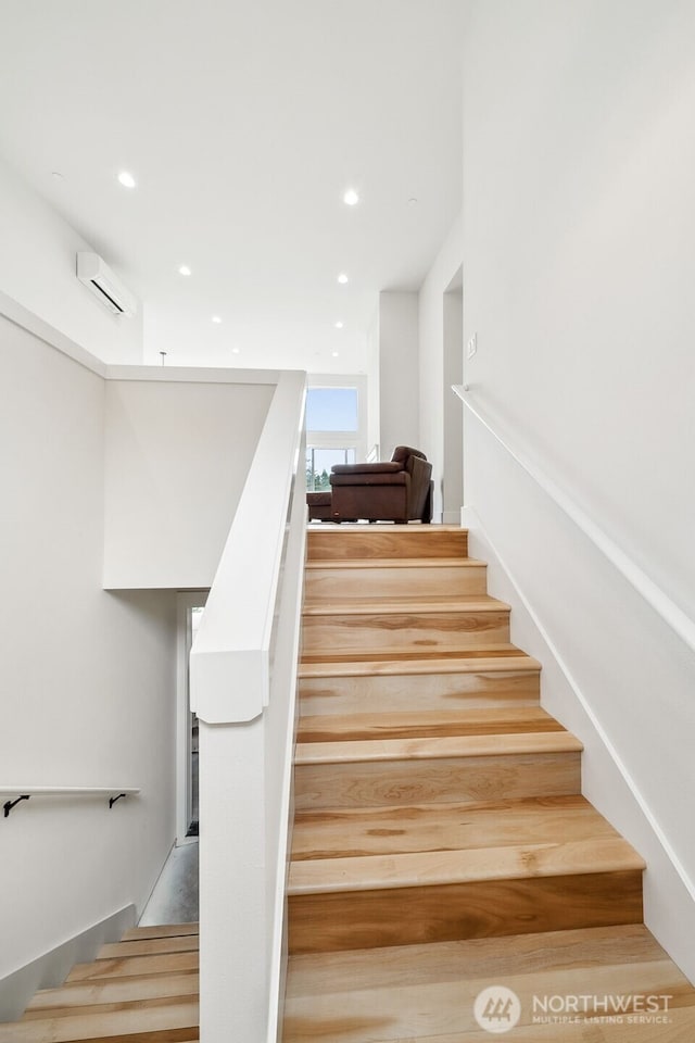 stairs with an AC wall unit and recessed lighting