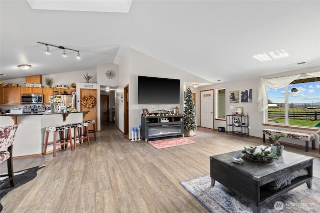 10893 Brick Mill Rd, Ellensburg, WA 98926 - living area with light wood-style flooring, track lighting, visible vents, and vaulted ceiling