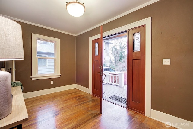 foyer with crown molding, wood finished floors, and baseboards