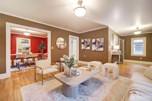 living room featuring baseboards, light wood-type flooring, and ornamental molding