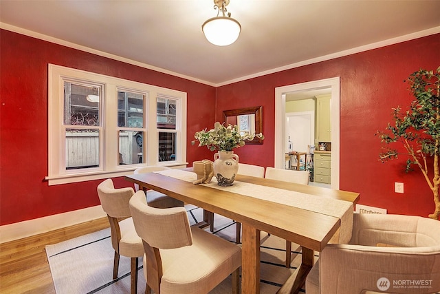 dining area featuring wood finished floors, baseboards, and ornamental molding