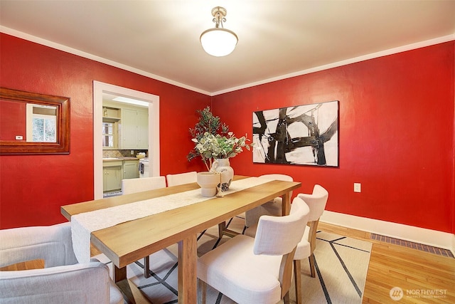 dining area with wood finished floors, baseboards, and ornamental molding