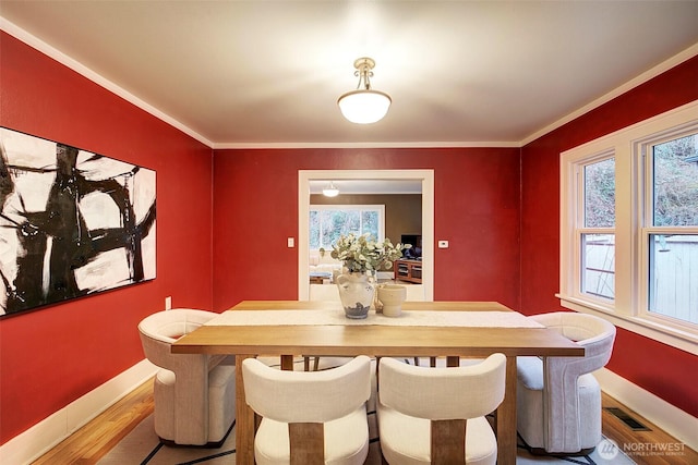 dining space with a healthy amount of sunlight, crown molding, and wood finished floors