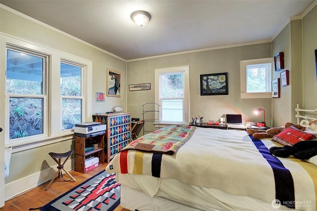 bedroom with crown molding, baseboards, and wood finished floors